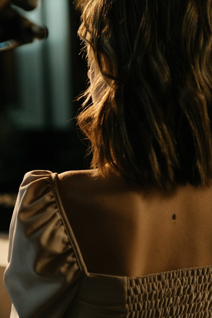Back view of a woman with elegant dress, highlighting her style in a dimly lit bar atmosphere.